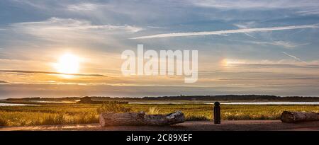 Schöner Sommeruntergang über einer Küste mit Parhelion, Sonnenhund auf der rechten Seite. Stockfoto