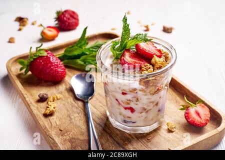 Glas Tasse mit Erdbeeren Joghurt Dessert auf Holzplatte Stockfoto