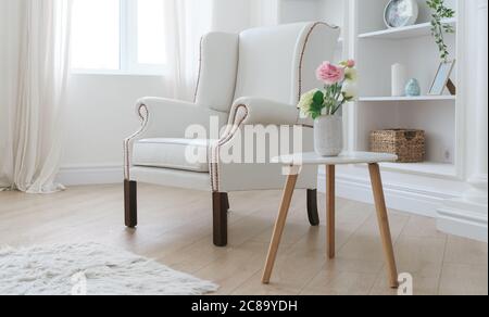 Ledersessel in Weiß und moderner Holztisch mit Blumenvase in hellem Raum Stockfoto