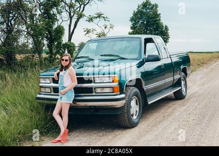 Teen Mädchen schiefen gegen einen grünen LKW geparkt entlang ein Dirt Road Stockfoto