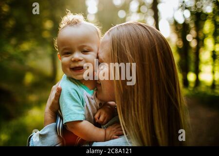 Glücklich Mutter kuscheln Baby junge draußen im Wald Stockfoto