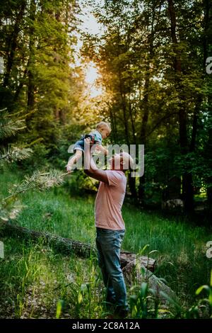 Vertikale Porträt von Papa hält Säugling Sohn in der Luft Stockfoto