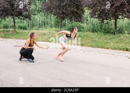 Junge Frau während des Work-out mit Trainer läuft im Park Stockfoto