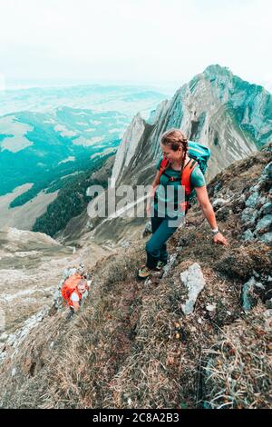 Zwei aktive Bergsteigerinnen besteigen steilen Grasberg in CH Stockfoto