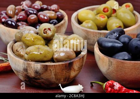 Nahaufnahme verschiedener Olivenarten in Holzschüsseln Stockfoto