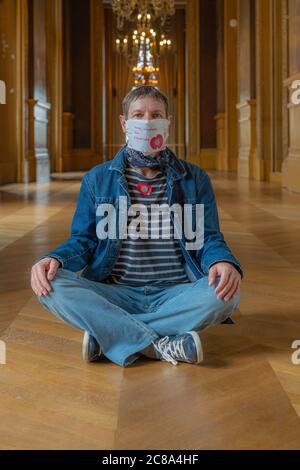 Paris, Frankreich - 06 19 2020: Eine maskierte Frau sitzt auf dem Holzboden des Opernhauses Stockfoto