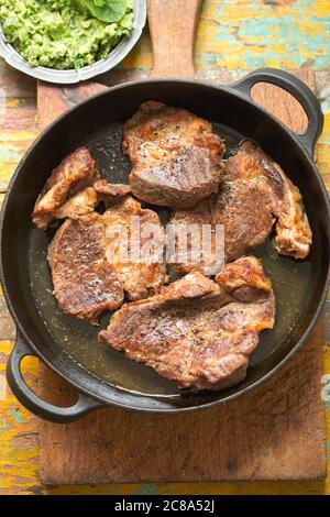 Schweineschulter in Weißwein mit Saubohnen & Kräuterpesto Stockfoto