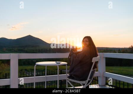 Junge Frau entspannend auf Dachterrasse mit Tasse Kaffee Stockfoto