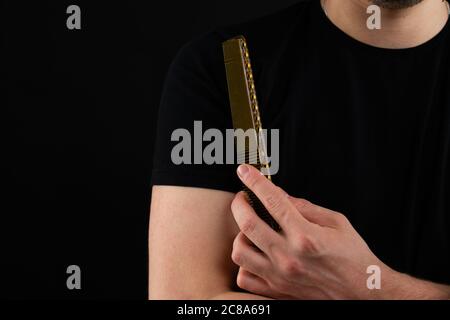 Zugeschnittenes Foto eines hübschen Barbiers in schwarzem T-Shirt mit Kamm Stockfoto