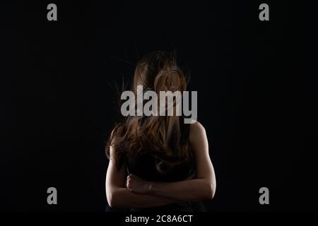 Frau mit Haaren über ihrem Gesicht, hält die Hände zusammen Stockfoto