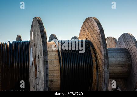 Schwarzes Kabel auf großen Holztrommeln. Stockfoto