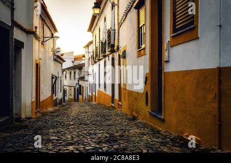 Sonnenuntergang in den Pfeilgassen von Evora, der Hauptstadt der Alentejo Region in Portugal, berühmt für seine traditionellen weißen und gelben Häuser Stockfoto