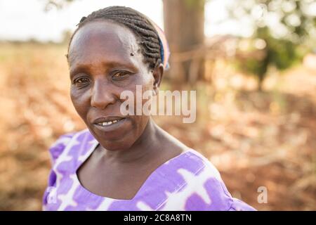 Porträt einer Frau mit einem düsteren Ausdruck in einer trockenen Landschaft im Makueni County, Kenia, Ostafrika. Stockfoto