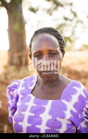 Porträt einer Frau mit einem düsteren Ausdruck in einer trockenen Landschaft im Makueni County, Kenia, Ostafrika. Stockfoto