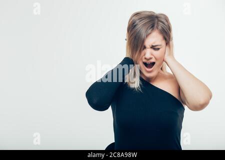 Schöne junge Frau mit Haarknoten mit Unzufriedenheit Blick verstopft ihre Ohren verärgert mit Lärm wollen Stille und ruhige Atmosphäre exha Stockfoto