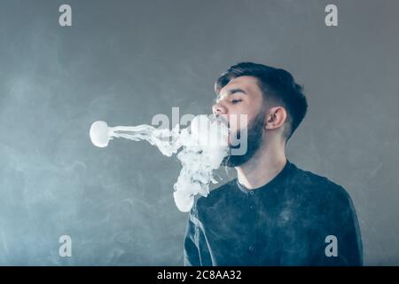 Männer mit Bartvape und produse Dampfringe Stockfoto