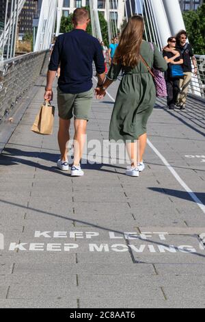 London, Großbritannien. Juli 2020. Die Meldungen „Keep Left, Keep Moving“ auf der Golden Jubilee Bridge erinnern die Londoner daran, Abstand zu halten und sich auf einer Seite der Brücke zu halten. Maskentragen und soziale Distanzierung scheinen zur „neuen Normalität“ zu werden, da sich immer mehr Menschen an die neuen Richtlinien und Empfehlungen gewöhnen. Kredit: Imageplotter/Alamy Live Nachrichten Stockfoto