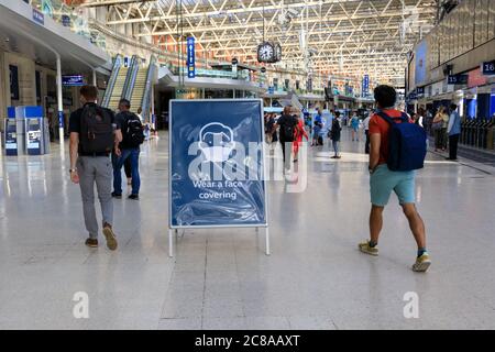 London, Großbritannien. Juli 2020. Ein Schild "Wear a Face covering" erinnert Pendler in Waterloo Station daran, ihre Masken zu tragen. Maskentragen und soziale Distanzierung scheinen zur „neuen Normalität“ zu werden, da sich immer mehr Menschen an die neuen Richtlinien und Empfehlungen gewöhnen. Kredit: Imageplotter/Alamy Live Nachrichten Stockfoto