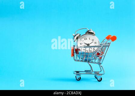 Warenkorb mit Wecker auf blau, Kauf Zeitkonzept Stockfoto