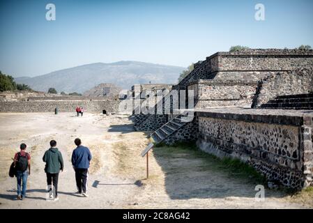 TEOTIHUACAN, Mexiko – Besucher spazieren entlang der Avenue of the Dead, der Hauptdurchgangsstraße der antiken mesoamerikanischen Stadt Teotihuacan. Dieser breite, gerade Boulevard erstreckt sich durch das Herz der archäologischen Stätte und bietet einen beeindruckenden Blick auf die monumentalen Pyramiden und Strukturen, die seinen Weg säumen. Stockfoto