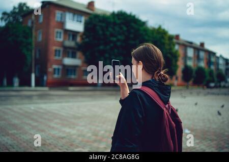 Porträt einer jungen Frau, die mit ihrem Smartphone die Stadtlandschaft fotografiert. Erwachsene weibliche Touristen, die Fotos auf dem Handy. Stockfoto