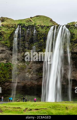 Bach des Seljalandfoss Wasserfall fällt vom Berg mit Menschen vor, Island Stockfoto