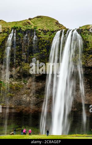 Bach des Seljalandfoss Wasserfall fällt vom Berg mit Menschen vor, Island Stockfoto