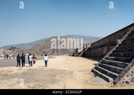 TEOTIHUACAN, Mexiko – Besucher spazieren entlang der Avenue of the Dead, der Hauptdurchgangsstraße der antiken mesoamerikanischen Stadt Teotihuacan. Dieser breite, gerade Boulevard erstreckt sich durch das Herz der archäologischen Stätte und bietet einen beeindruckenden Blick auf die monumentalen Pyramiden und Strukturen, die seinen Weg säumen. Stockfoto