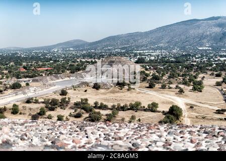 TEOTIHUACAN, Mexiko – Ein Panoramablick auf die Mondpyramide von der Spitze der Sonnenpyramide in Teotihuacan. Diese Perspektive zeigt die Pracht der antiken mesoamerikanischen Stadt. Die Avenue of the Dead erstreckt sich zwischen diesen beiden monumentalen Bauten und bietet einen atemberaubenden Einblick in die Stadtplanung dieser präkolumbianischen Metropole. Stockfoto