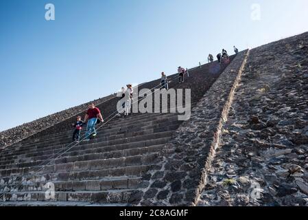 Pyramide der Sonne Besucher auf Teotihuacan Mexiko // TEOTIHUACAN, Mexiko – Besucher klettern die steilen Stufen der Pyramide der Sonne an der archäologischen Stätte Teotihuacan. Dieses monumentale Gebäude, eine der größten antiken Pyramiden Amerikas, erhebt sich etwa 216 Fuß (66 Meter) hoch und misst etwa 720 Fuß (220 Meter) an seiner Basis. Die Pyramide wurde um 100-450 n. Chr. von der antiken Teotihuacan-Zivilisation errichtet, deren Identität den Archäologen weitgehend unbekannt ist. Teotihuacan war eine der größten Städte in der Antike, mit einer Bevölkerung, die möglicherweise r Stockfoto