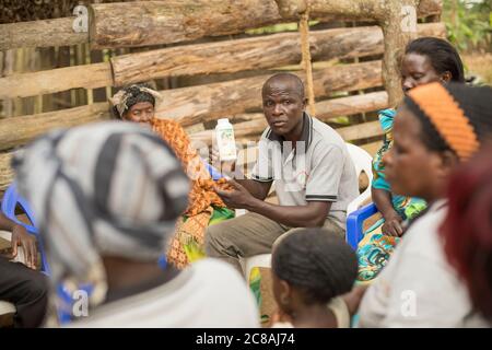 Ein Landarbeiter bildet Kleinbauern aus und verkauft sie bei einem Dorfgemeinden-Treffen im Kyotera District, Uganda. Stockfoto