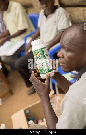 Ein Landarbeiter bildet Kleinbauern aus und verkauft sie bei einem Dorfgemeinden-Treffen im Kyotera District, Uganda. Stockfoto