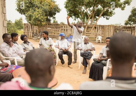 Ein Landarbeiter bildet Kleinbauern aus und verkauft sie bei einem Dorfgemeinden-Treffen im Kyotera District, Uganda. Stockfoto