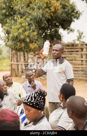 Ein Landarbeiter bildet Kleinbauern aus und verkauft sie bei einem Dorfgemeinden-Treffen im Kyotera District, Uganda. Stockfoto