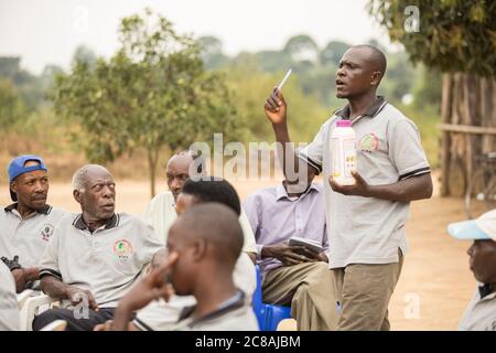 Ein Landarbeiter bildet Kleinbauern aus und verkauft sie bei einem Dorfgemeinden-Treffen im Kyotera District, Uganda. Stockfoto