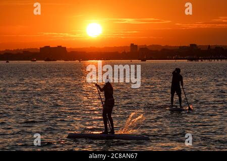 Poole, Großbritannien. Juli 2020. Paddelboarder bei Sonnenuntergang im Poole Harbour in Dorset von der Halbinsel Sandbanks aus gesehen. Kredit: Richard Crease/Alamy Live Nachrichten Stockfoto