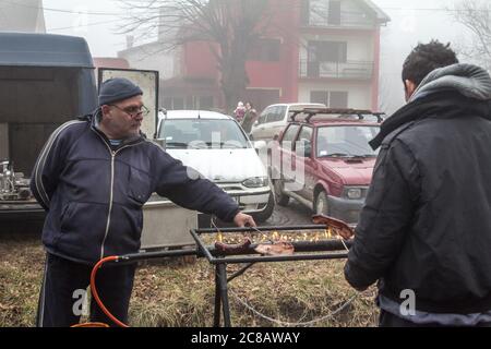 KACAREVO, SERBIEN - 18. FEBRUAR 2017: Zwei Männer grillen Fleisch und Wurst auf einem Markt in Serbien, in einem typischen Rostilj, einem traditionellen Grill in der Ba Stockfoto