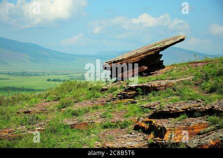 Ein großer flacher Opferstein, der auf einem Hügel aufgestellt ist. Bergkette Truhen, Chakassien, Südsibirien, Russland. Stockfoto