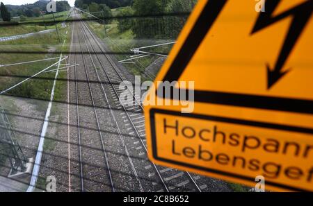 22. Juli 2020, Bayern, Weißensberg: Auf einer Brücke über die Bahnstrecke München-Lindau, die mit neuen Masten und Stromleitungen ausgestattet wurde, warnt ein Schild vor Hochspannung. Zweieinhalb Jahre lang war die Bahn an der Elektrifizierung der 155 Kilometer langen Strecke beteiligt, und nun steht das Projekt kurz vor der Fertigstellung (dpa: "Vom Pionier zum Verrückten: Warum den bayerischen Schienen der Strom fehlt"). Foto: Karl-Josef Hildenbrand/dpa Stockfoto