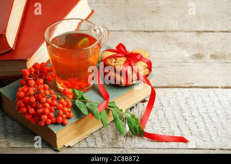 Lesen im Herbsttag. Retro Herbstbücher und Tee, Eberesche, Beere, Hagebutte auf einem Holztisch. Gemütliche Herbststimmung, Copy Space, wärmende beruhigende Lasure t Stockfoto