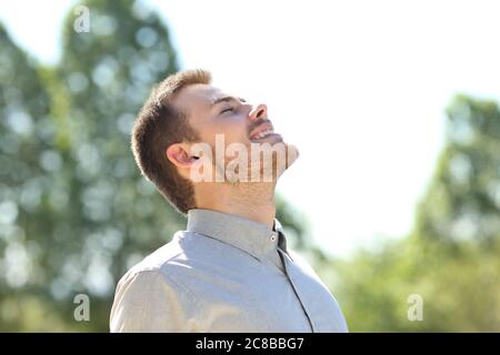 Glücklicher Mann atmet frische Luft auf einem Park im Freien mit grünen Bäumen stehen Stockfoto