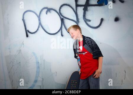 Auf diesem atemberaubenden Foto zeigen sich die Skateboard-Fähigkeiten eines blonden Jungen Stockfoto