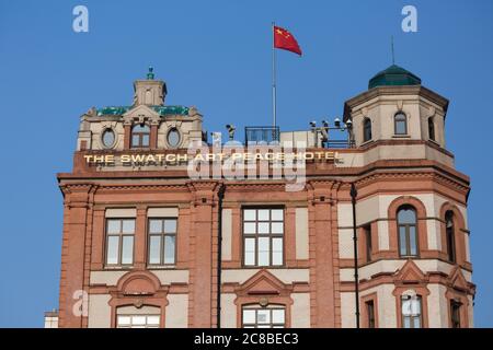 Shanghai, China - 18. April 2018: Nahaufnahme des Swatch Art Peace Hotels - eines der berühmtesten Hotels in Shanghai. Mit chinesischer Flagge und Vermessungszeichen Stockfoto