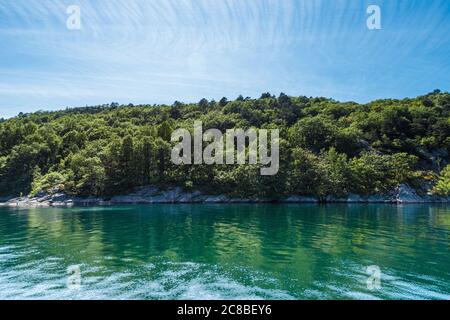 Felsige Klippen mit Bäumen bedeckt. Fast grünes Wasser. Stockfoto