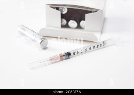 Spritzennadel und Impfphals auf weißem Tisch. Prävention Immunisierung oder medizinisches Konzept. Stockfoto