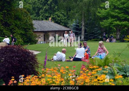 Zwei Paare, die auf dem Rasen ein Picknick im RHS Garden Harlow Carr, Harrogate, Yorkshire, England, Großbritannien. Stockfoto