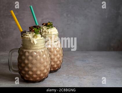 Selektiver Fokus. Süßer Schokoladenmilchshake mit Eis, Kaffee und Schlagsahne in einem Glas-Einmachglas serviert. Stockfoto