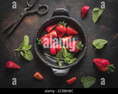 Schwarze Schale mit frischen Erdbeeren, alte Schere auf Vintage-Tisch. Overhead-Aufnahme. Stockfoto