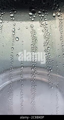 Weicher Fokus auf Textur von klaren Wassertropfen auf transparentem Glas. Abstrakter Hintergrund mit Kondensation von Tropfen auf nasser Glasoberfläche Stockfoto