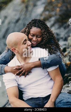 Romantisches Paar am felsigen Ufer lachen und verbinden. Stockfoto